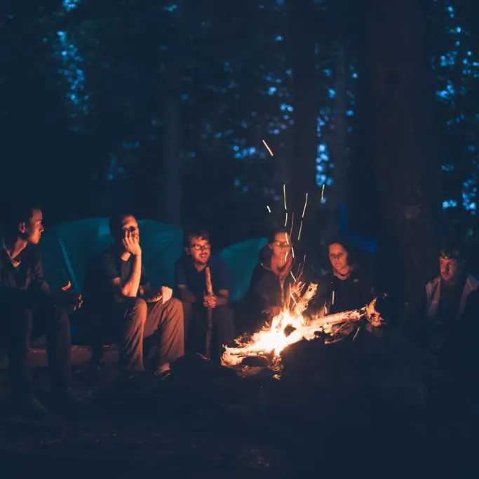 groep jongeren in het donker zittend om een kampvuur