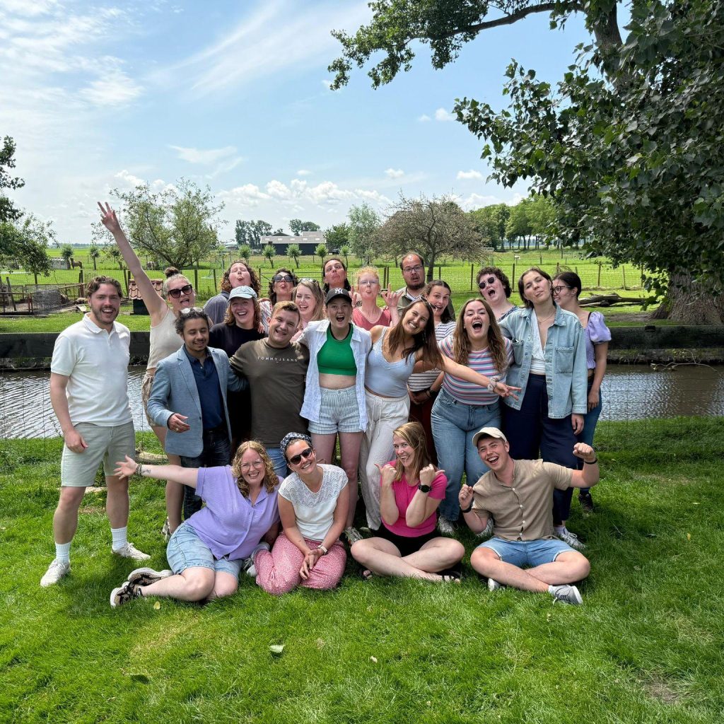 groep jongeren op grasveld die met z'n allen poseren voor de foto, blij en vrolijk